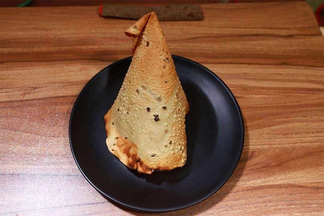 Golden crispy samosa with spicy filling served on a black plate at Biryani Place, a popular restaurant known for flavorful biryanis and Indian snacks in a cozy setting.
