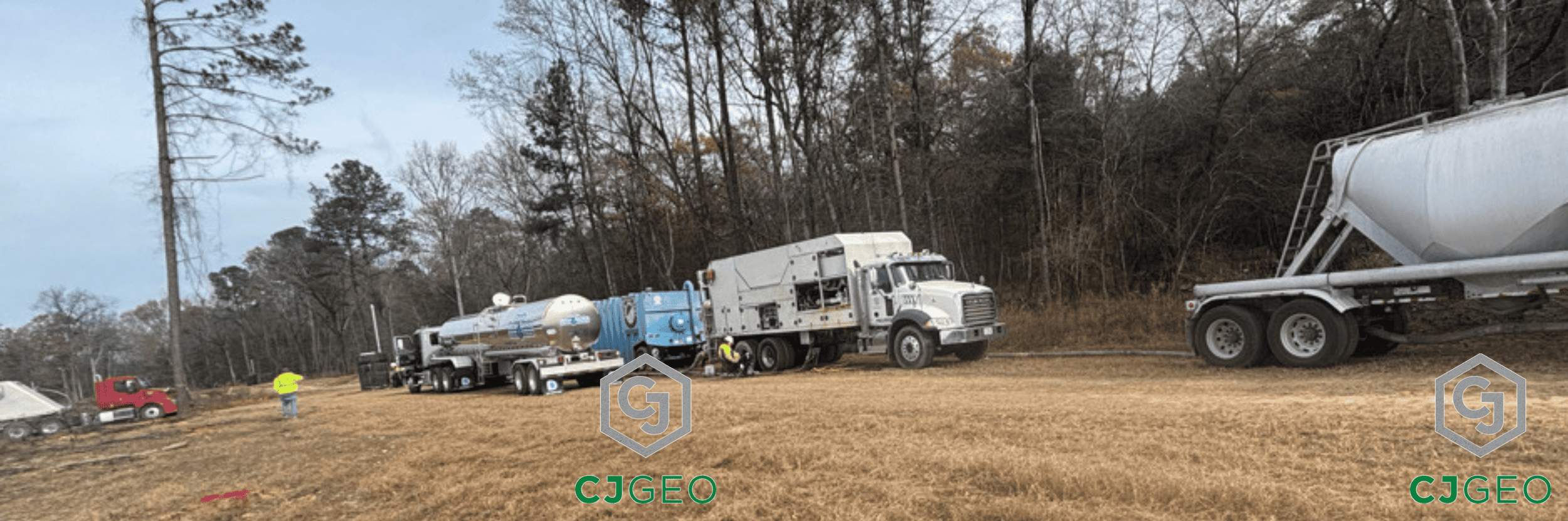 CJGeo batch plant, water truck, frac tank and two cement tankers onsite at a construction site in a field