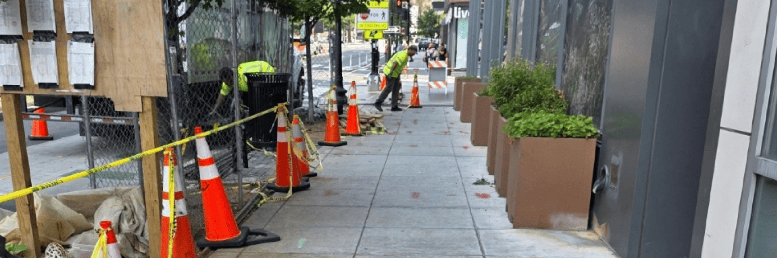 An urban construction site on a sidewalk with cones and a polyurethane grouting truck.
