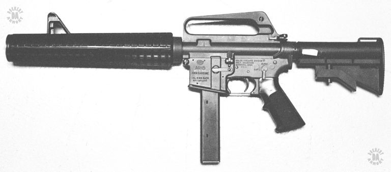 The left side of the Knights Armament Co. conversion of a Colt Model 635 submachinegun into an integrally suppressed version. The suppressor surrounds the short barrel and extends in front of the muzzle. The entire suppressor body has been encased with a special set of M16A2 hand guards. The standard front sight of the Model 635 is retained and extends up above the hand guards. PHOTO CREDIT: Kevin Dockery