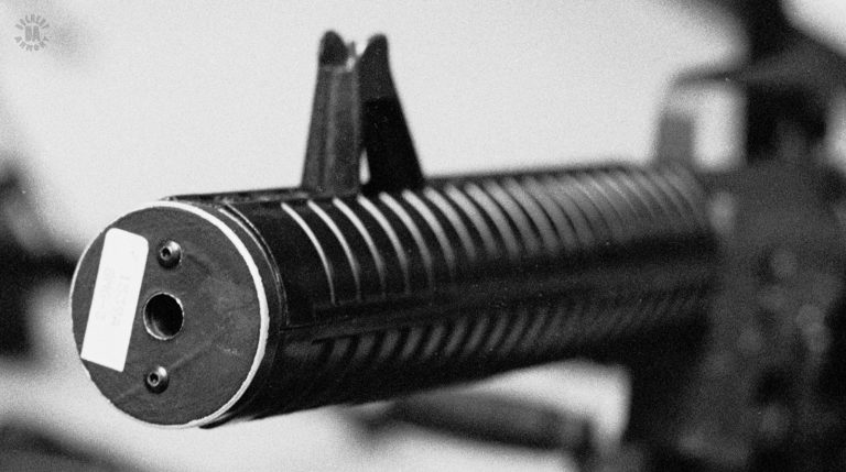 A right side muzzle view of the suppressed Knights Armament Co. conversion of a Colt Model 635 submachinegun. The muzzle cover is a flat plate held on to the weapon by the two round-headed screws. PHOTO CREDIT; Kevin Dockery