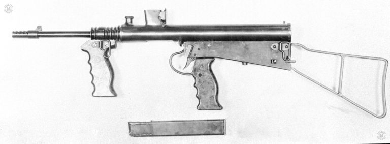 Left side view of the Owen Mk I/42 with the magazine removed and laying below the weapon. The rectangular block above the trigger is the safety-selector switch in the forward (safe) position. Placing the switch in the central detent point puts the weapon on semiautomatic. With the switch in the rearward position (third detent) the weapon fires on full automatic. PHOTO CREDIT: US Army