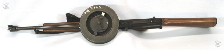 A top side view of the American 180 with the 177-round drum magazine in place. The winder that drives the magazine is visible in the central well of the drum. Written on the outside top edge of the drum is the notice “. 3 1/2 Turns” indicating just how many turns to give the two lugs on the side of the winder to power the drum. PHOTO CREDIT: J. Purtillo