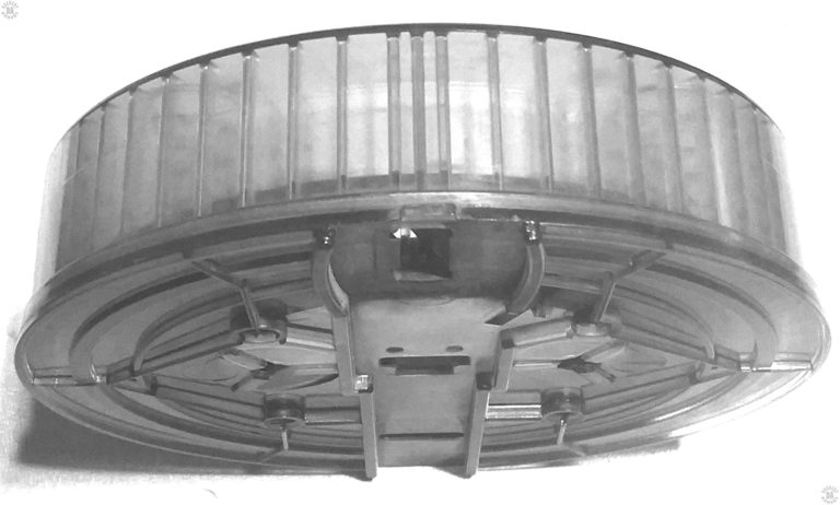 The is a lower rear side view of an empty 165-round lexan drum for the American 180. The winder is not in place on this specimen. The rectangular opening at the closest end of the bottom in this view is the feed opening for the ammunition. The vertical spacers on the inside of the drum are to separate the rounds of 22 long rifle from on another. The drum will hold three layers of 55-rounds each of ammunition in spirals within the magazine. Each round is loaded with the bullet pointing to the center of the drum. PHOTO CREDIT: DCS