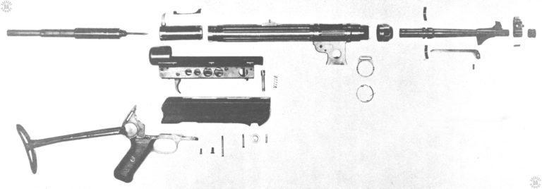 A detailed disassembled view of the MP38. The lower receiver in the center of the picture has not been broken down. The very distinctive and widely copied telescoping mainspring assembly is at the upper far left of the picture. In front of the mainspring assembly is the bolt with is curved cocking handle uppermost. The small curved piece above the bolt is the extractor. PHOTO CREDIT: US Army