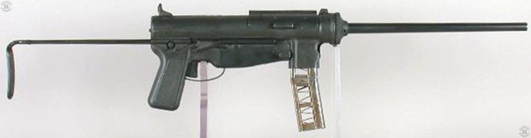 The 35.8 cm (14 inch) barreled version of the experimental T29 submachinegun. The magazine has been built up from two 15-round M1 Carbine magazines welded end-to-end. The sides are cutaway to view the ammunition stacks within the mag. The very long safety and ejection port cover is closed on top of the weapon. The housing assembly is very much like that of the M3A1 submachinegun in that it has no allowance for a cocking handle. The stock is fully extended. PHOTO CREDIT: Springfield Armory National Historical Site