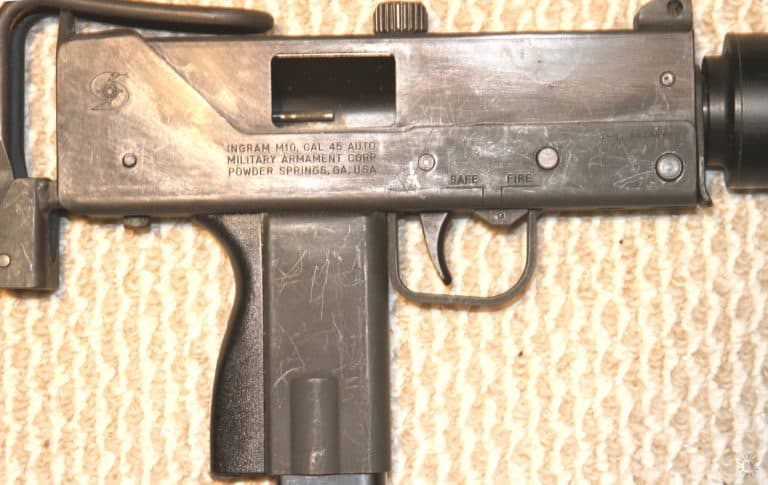 The marking on an Ingram M10 45. The sliding safety on the outside of the trigger guard is slid into the forward, fire, position. The ejection rod can be seen inside the open ejection port. At the center rear of the lower receiver is the COBRAY emblem of the Military Armament Corporation (MAC). The emblem is of a mythical part Cobra and part Moray Eel. This weapon was made at the original Powder Springs, Georgia facility. PHOTO CREDIT: Kevin Dockery