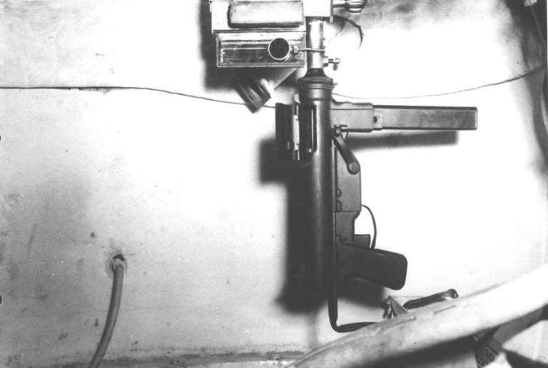 The M3 curved barrel mounted within the turret of an M4 Sherman tank. The device has an M3 submachinegun inserted and mounted in place. The weapon is cocked and ready to fire. It would be moved and aimed with the T20 optical periscope next to the barrel. PHOTO CREDIT: Friends of the Tank Museum.