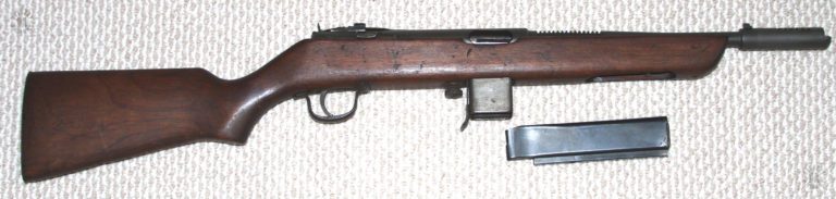 The right side of the Reising M50 with the 20 round magazine removed and laying below the weapon. The curved side of the top of the magazine can be seen in this illustration. The smooth sides and top of the magazine made the design particularly susceptible to jamming from dust, sand, or mud getting into the nody of the magazine and blocking the follower from movement. PHOTO CREDIT: Kevin Dockery