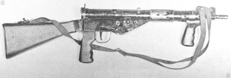 A right-side view of the Sten Mk V. This specimen has the vertical forward handgrip, distinctive to the early Mk v weapons. Wear on the action from the use of the forward grip caused it to be removed by general order. The bolt is in the forward position and the Mk 5 safety cocking handle has been pressed inwards, locking the bolt in position. The buttstock on this specimen is the Mk3 version with the curved buttplate assembly. PHOTO CREDIT: US ARMYA right-side view of the Sten Mk V. This specimen has the vertical forward handgrip, distinctive to the early Mk v weapons. Wear on the action from the use of the forward grip caused it to be removed by general order. The bolt is in the forward position and the Mk 5 safety cocking handle has been pressed inwards, locking the bolt in position. The buttstock on this specimen is the Mk3 version with the curved buttplate assembly. PHOTO CREDIT: US ARMY