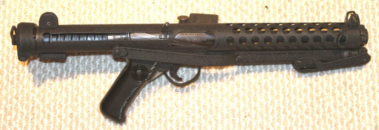 The Sterling L2A3 with the stock folded and no magazine loaded in place. The bolt is forward in the uncocked position. This photo demonstrates the compact size of the weapon. Even with the stock folded, the submachinegun can be accurately and quickly fired at a suddenly appearing target when used with both hands. PHOTO CREDIT: KEVIN DOCKERY