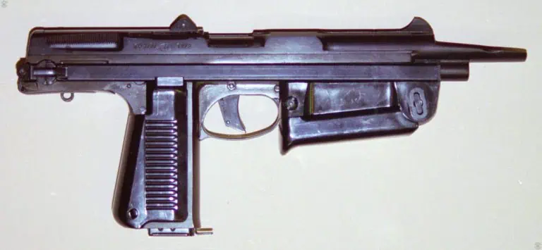 A right-side view of an uncocked Wz63 fitted with a 15-round magazine. The front handgrip is folded up against the bottom of the receiver, giving this specimen its most compact configuration. The serrations to allow for easier cocking are visible at the upper rear of the slide. The trough-like muzzle compensator is extended forward from the uncocked slide. PHOTO CREDIT: KEVIN DOCKERY