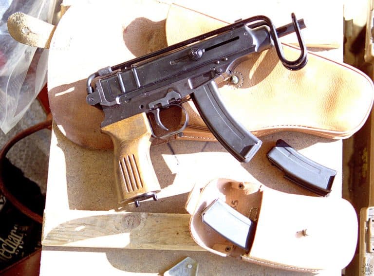 The right-side of a Vz-61 Skorpion with some of the materials issued with it. The bolt on the weapon is locked back on an empty magazine. Fitted with a 20-round magazine as seen here, the weapon will not fit into the hip holster it is laying on. To fit in the holster, the Vz-61 would have to be loaded with the 10-round magazine laying on the table between the holster and the magazine pouch. The shape of the pouch is due to the strong curve on the 20-round magazines (2) that it normally holds. PHOTO CREDIT: KEVIN DOCKERY