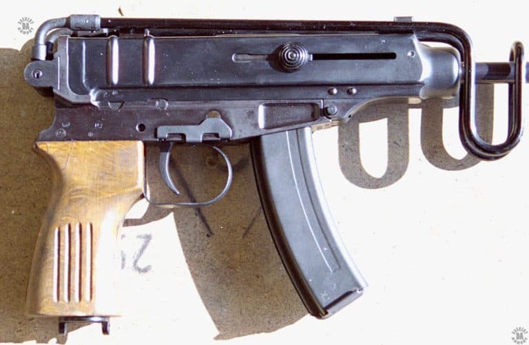 The right-side of a Vz-61 Skorpion. The weapon is loaded with a 20-round magazine. The bolt is locked back on an empty chamber as indicated by the cocking knobs being two-thirds of the way back in the slot it travels in. The folding stock is latched in place by the spring slip at the base of the front sight. The two-lugged cap at the bottom of the wooden pistol grip retains the rate reducing mechanism inside of the grip. PHOTO CREDIT: KEVIN DOCKERY