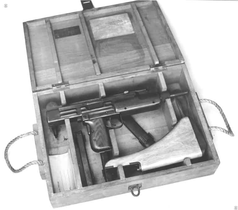 One of the first five pre-production Uzi submachine guns in its transportation crate. The crate is holding the weapon, with the stock removed, securely in cutouts. The same holds for the wooden stock on the other side of the box. Underneath the weapon is two 30-round magazines as well as the bayonet in its scabbard. At the right end of the box is the carry strap for the weapon. PHOTO CREDIT: US NAVY HISTORICAL ARCHIVES