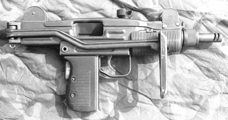 The right side of an unloaded Mini-Uzi. The stock is folded along the right side of the receiver where the bend is the stock strut clears the ejection port. This clearance allows the Mini-Uzi to be fired with the stock open or folded. With the stock folded, the buttplate can be used as a forward grip by the non-firing hand. The two slots cut near the muzzle of the barrel act as a compensator to help hold the weapon down in line with the target when fired on full automatic. The bolt is cocked to the rear on this specimen. PHOTO CREDIT: KEVIN DOCKERY