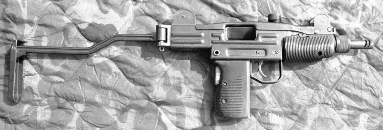 The right side of an unloaded Mini-Uzi with the stock extended. The two slots cut near the muzzle of the barrel act as a compensator to help hold the weapon down in line with the target when it is fired on full automatic. The L-shaped part at the front of the receiver is the lever to the ratchet that helps retain the barrel nut. The bolt is cocked to the rear on this specimen. PHOTO CREDIT: KEVIN DOCKERY