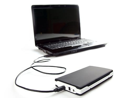 Black laptop connected by cable to portable external hard drive