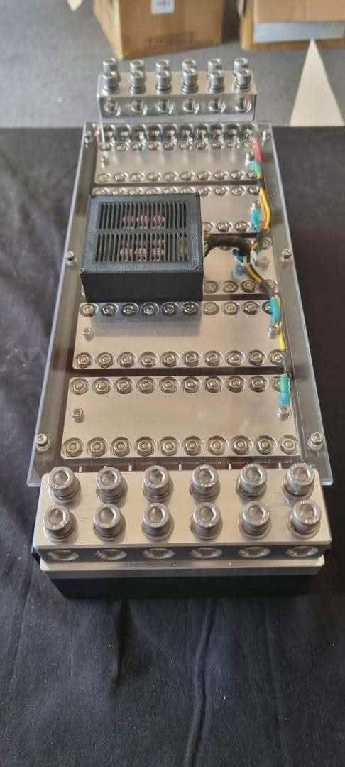 Rectangular metal electronic component with cylindrical connectors.