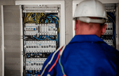 : Ein Bild eines Wartungsarbeiters, der den Sicherungskasten untersucht.