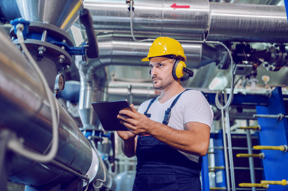 A maintenance worker inspecting an industrial boiler system.
