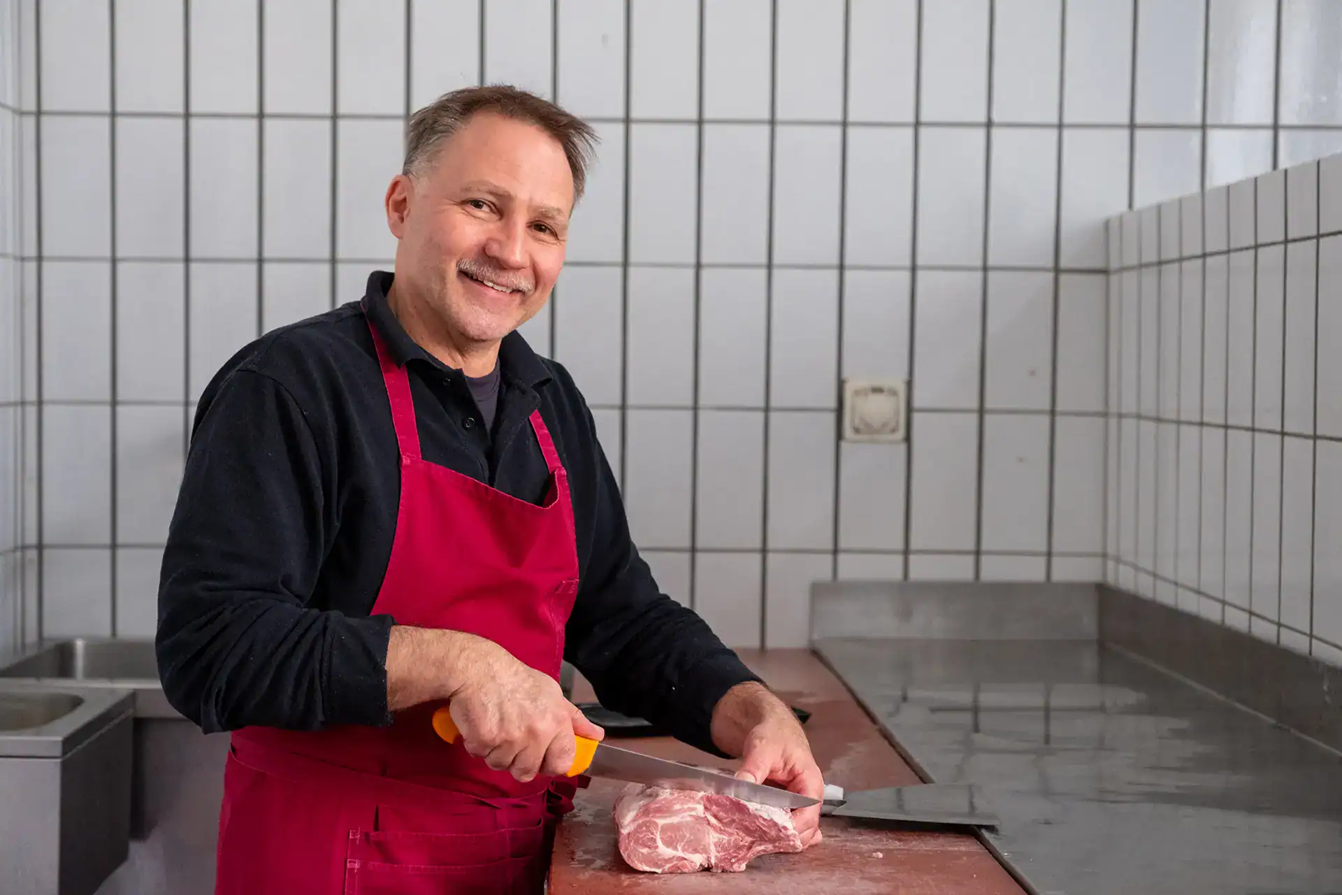 Metzger beim Zuschneiden eines Cotelettes.