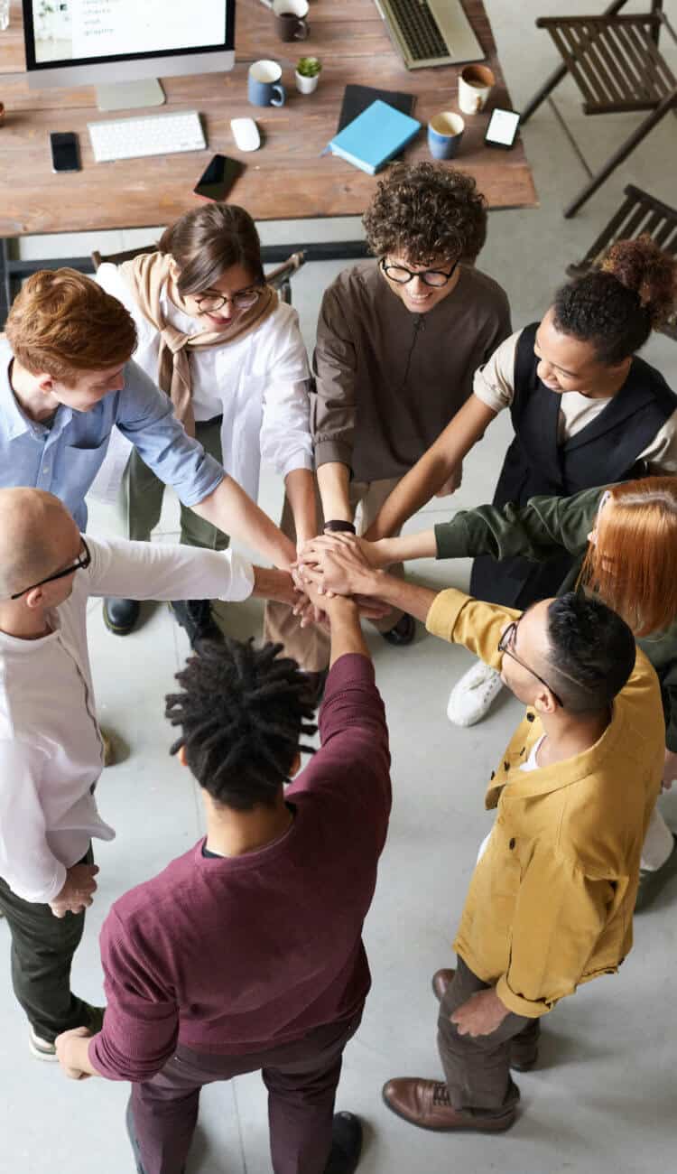 社員が円になり、中心に手を伸ばして重ね気持ちを高めている様子