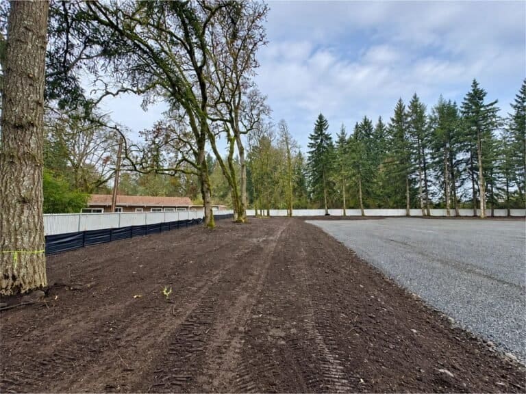 Graded lot bordered by gravel and tall trees in Deer Island, Oregon