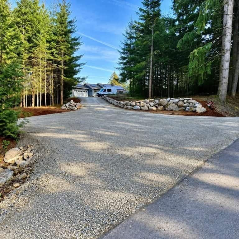 Wide gravel driveway entrance lined with trees in Rainier, Oregon