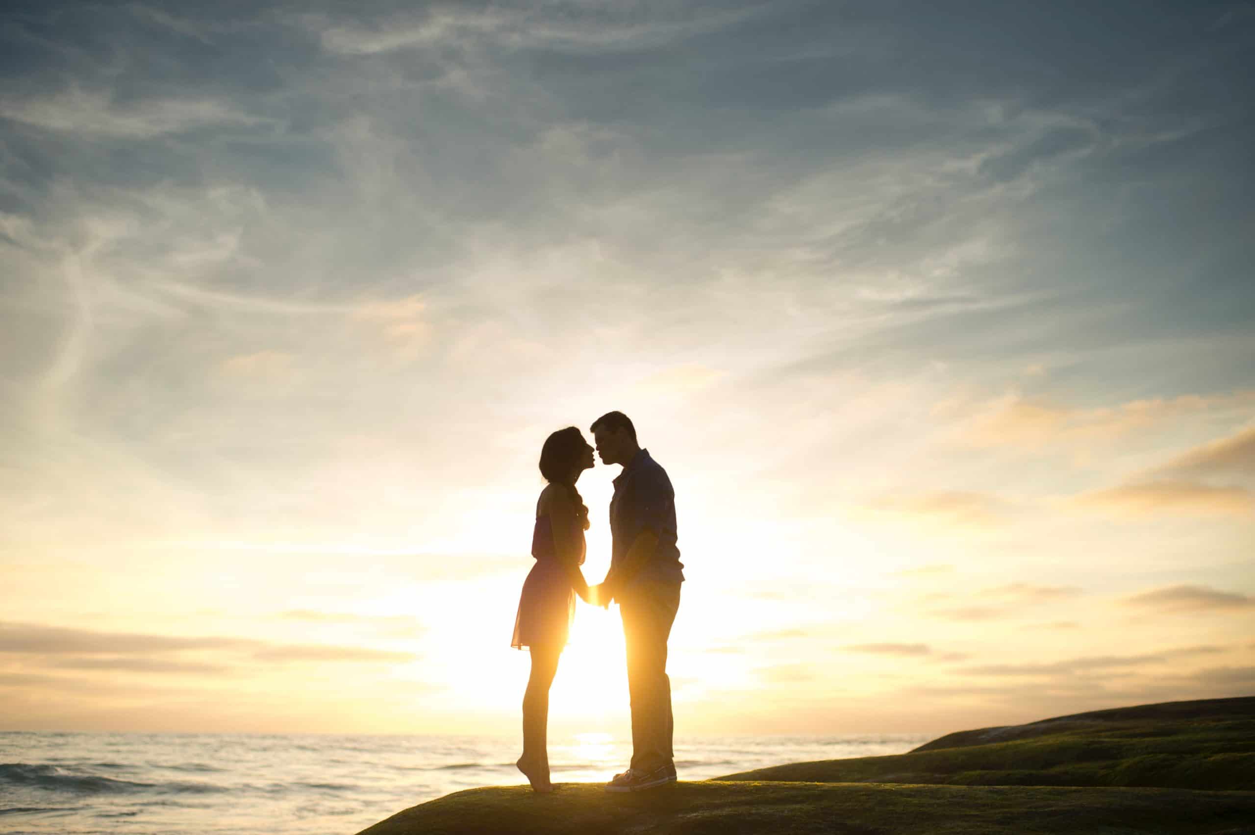 Sunset silhouetting a couple kissing because they chose to use a dating coach for over 50 singles and found each other.