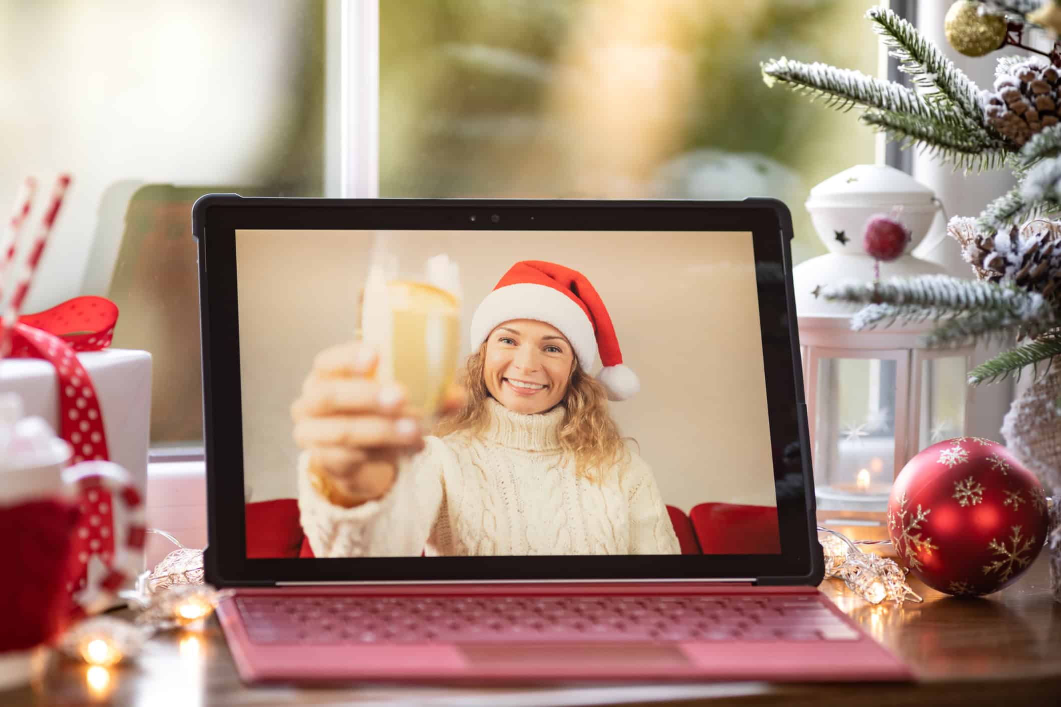 Woman in a Santa hat toasting her Zoom date.