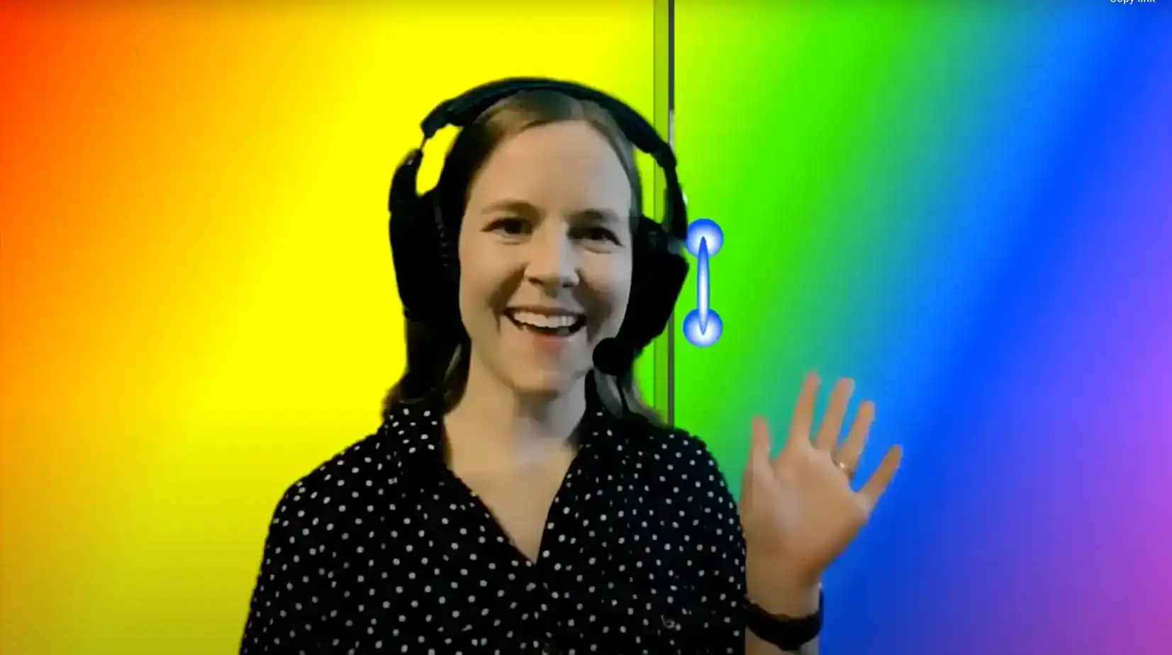 Kathryn smiling and waving at the camera with rainbow gradient background