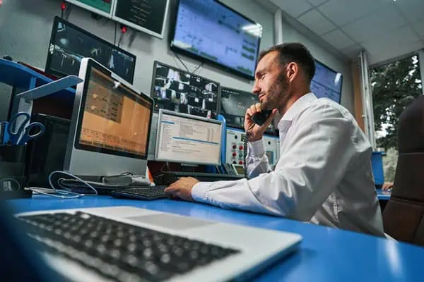 controle de processo 1 Data center operations professional talking on the phone while monitoring network stability through computer