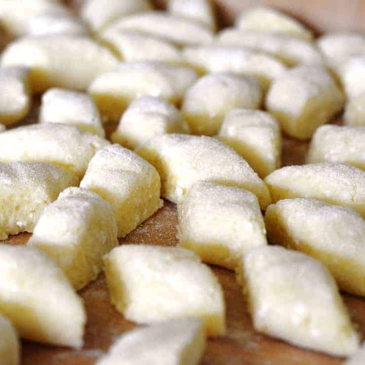 A tray of Polish gnocchi on a wooden cutting board.