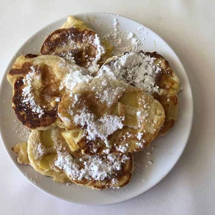 Plate of Polish pancakes sprinkled with powdered sugar.