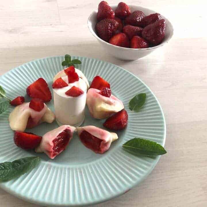 A plate with strawberry dumplings and mint on it.