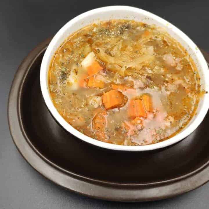 Authentic Polish Kapusniak recipe featuring sauerkraut, carrots, and cabbage in a delightful bowl of soup.