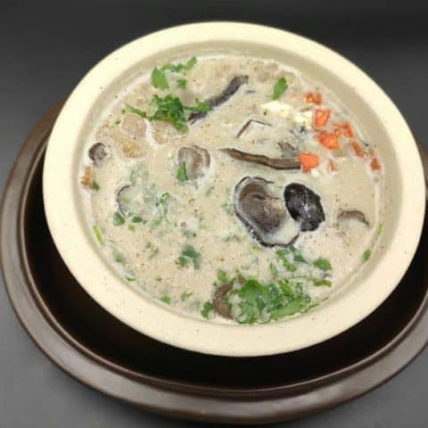 A flavorful bowl of Polish Dried Mushroom Soup [Zupa Grzybowa] with mushrooms in it.