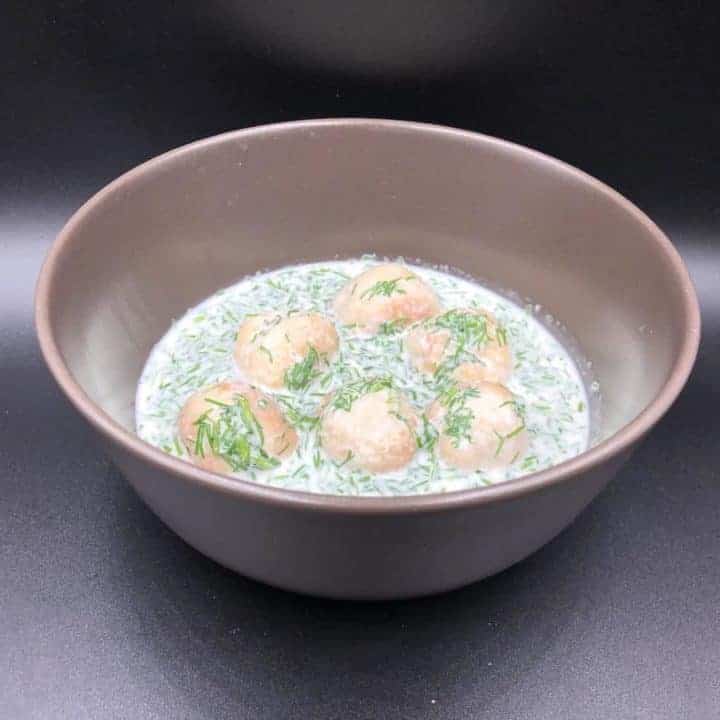 A bowl of soup with Polish meatballs in dill sauce.