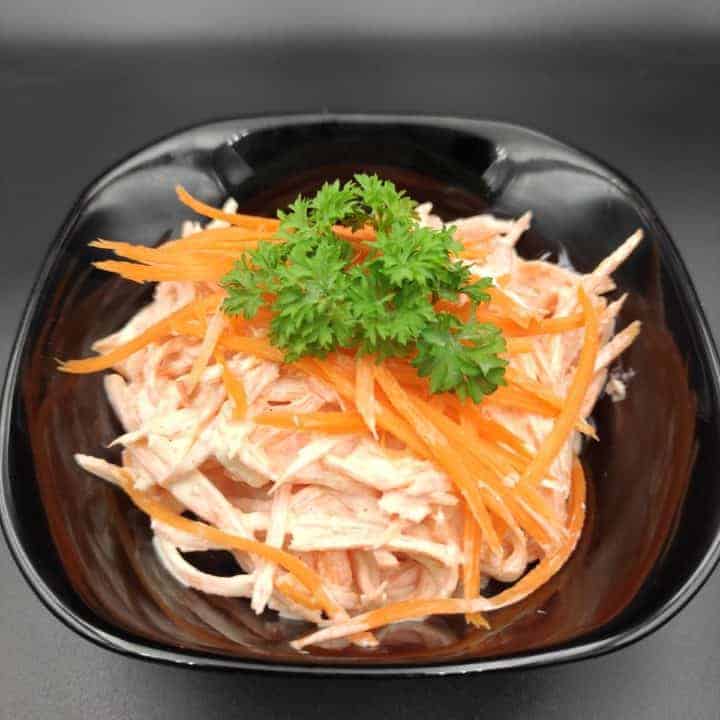 Polish surowka z marchewki polish carrot salad in a black bowl.