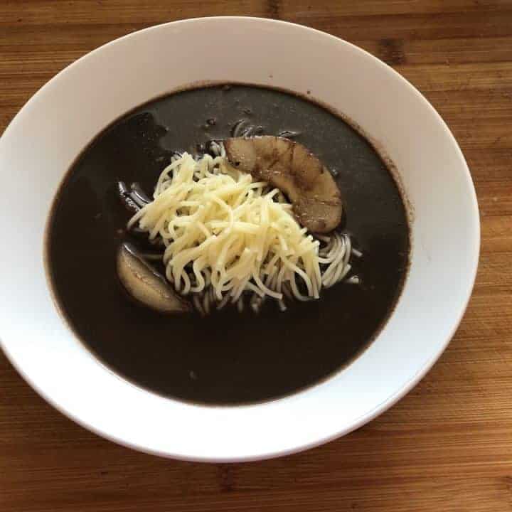 A bowl of black bean soup with cheese and Polish duck blood soup on top.