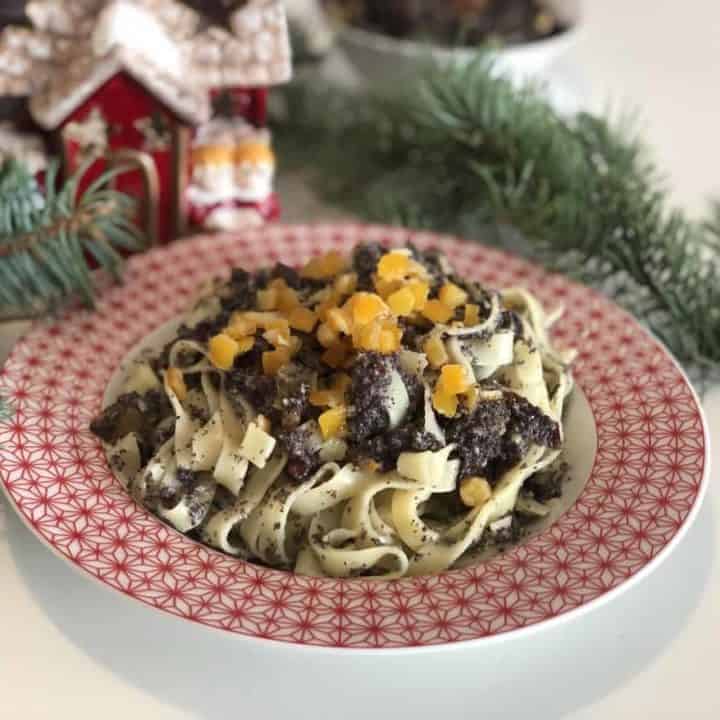 A plate of Polish Poppy Seed Noodles Recipe [Kluski Z Makiem] with meat and oranges on it.