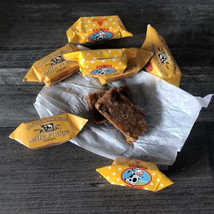 A box of chocolate biscuits and krowka Polish candy on a wooden table.