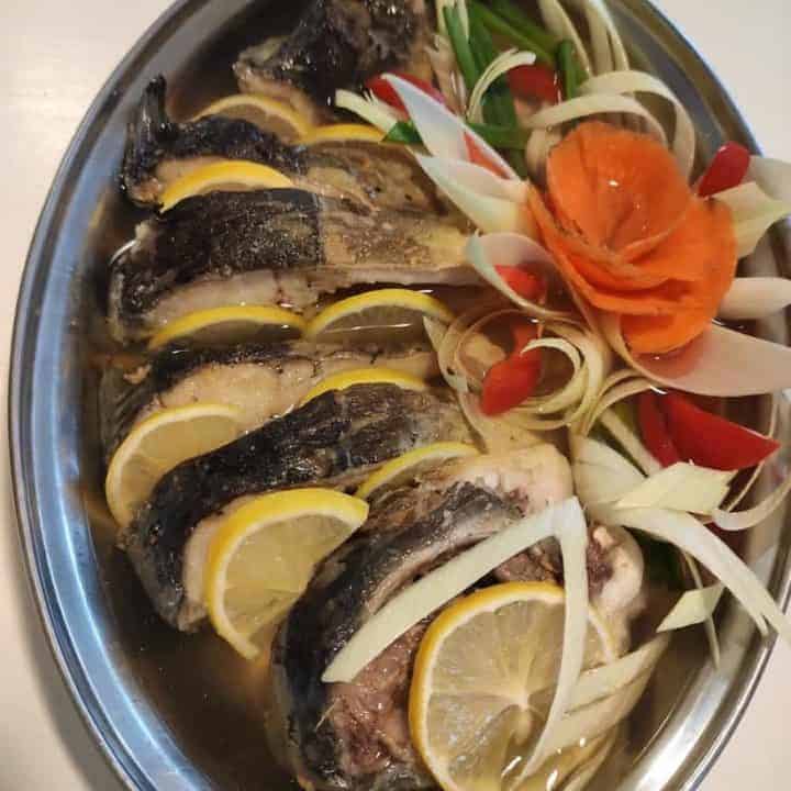 Carp with veggies in a steel dish.