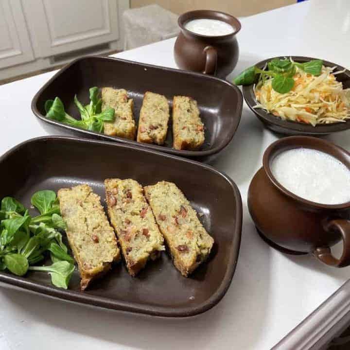 Three plates of food on a table next to a cup of milk, including a Polish potato babka recipe.