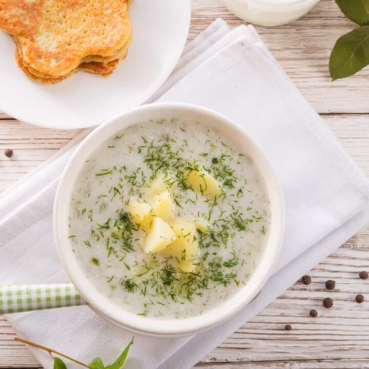 A bowl of Polish potato soup on a wooden table.