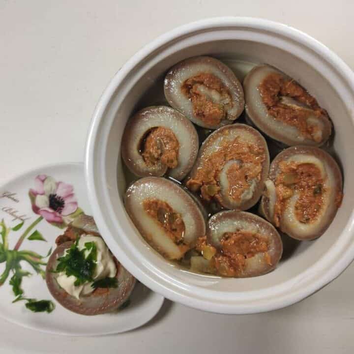 A bowl of stuffed clams and Polish herring rolls on a white plate.