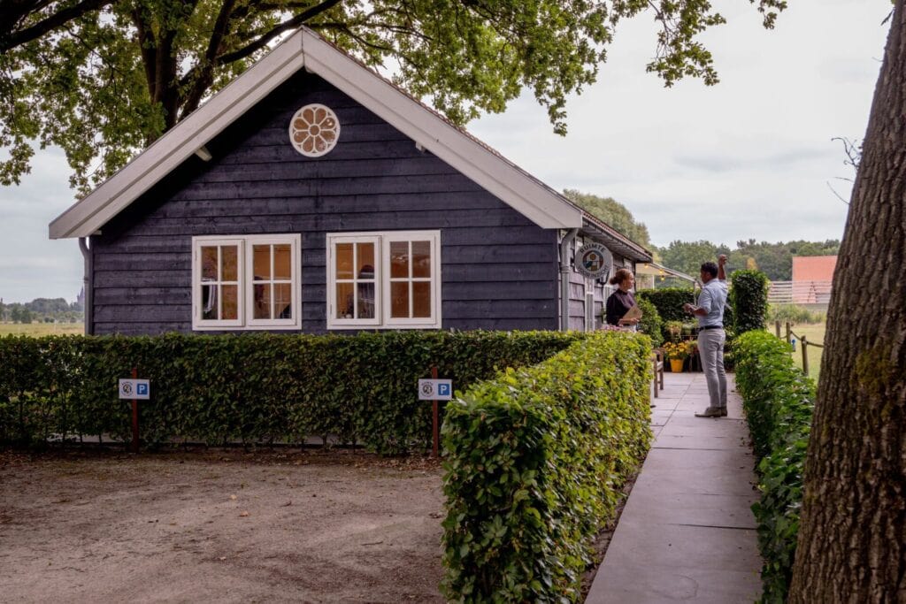 Vooraanzicht van privé vergaderlocatie in de natuur Ruimte voor Inzicht in Oisterwijk. Twee mensen ontmoeten elkaar bij de voordeur.