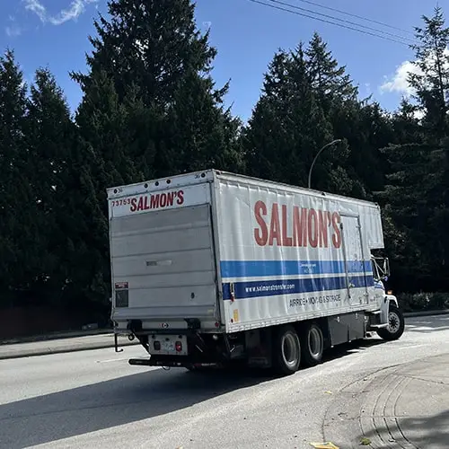 Salmon's moving truck on residential street with evergreen trees in background