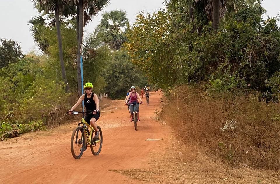Cyclists exploring Cambodian culture by bike near Tonle Sap Lake, riding through traditional villages, local markets, rice fields, and scenic countryside landscapes.